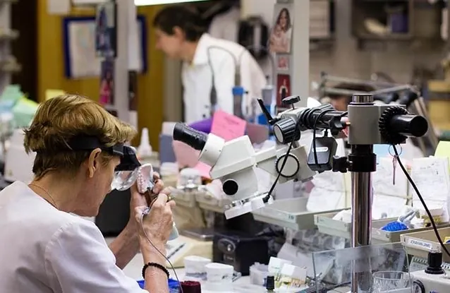 A technician checking a restoration under the microscope in the in-house laboratory.