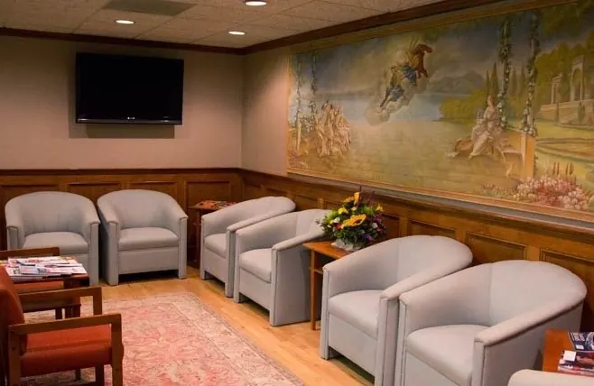 The practice's waiting room, grey armchairs beneath a painted mural.